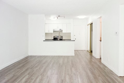 an empty living room and kitchen with white walls and wood floors