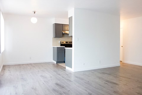 a living room and kitchen with wood floors and white walls
