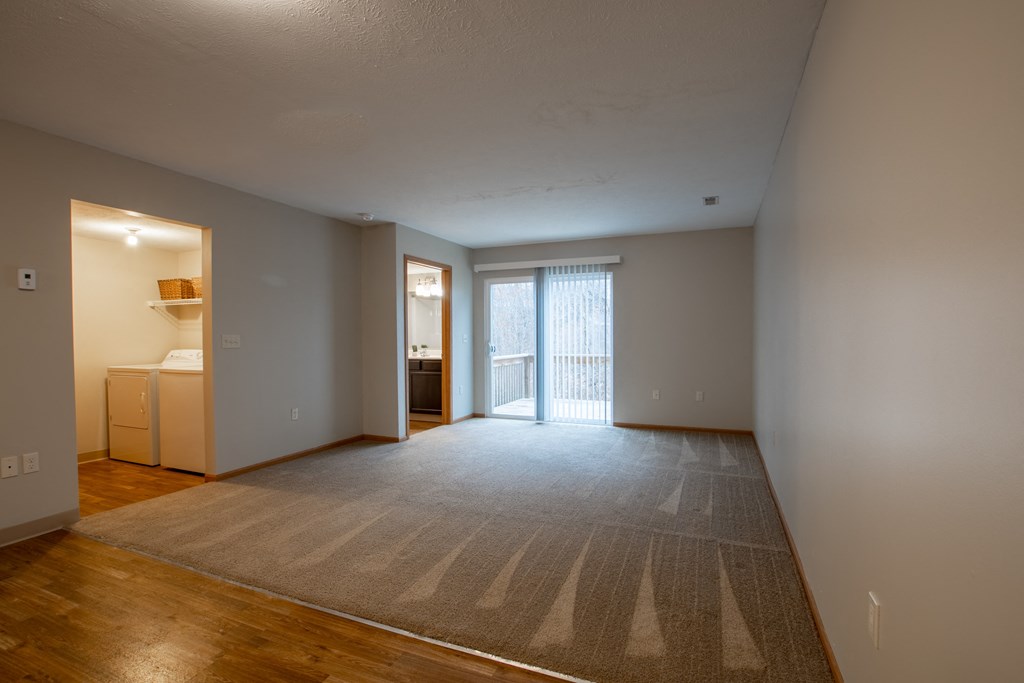 an empty living room with a rug and a door to a bathroom