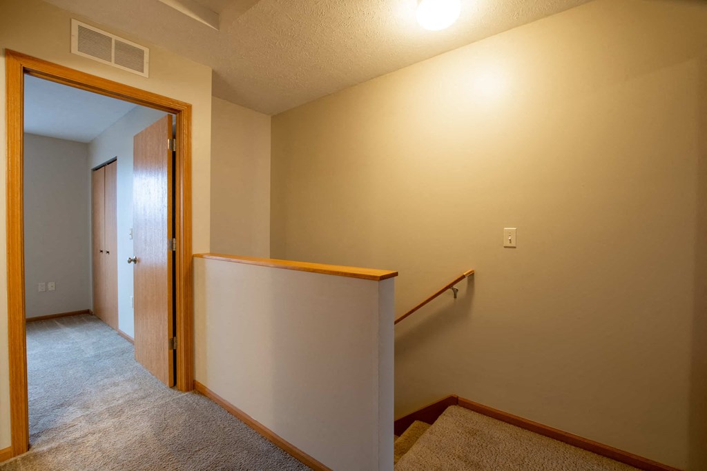 a landing area with a staircase and a door to a hallway with a door open