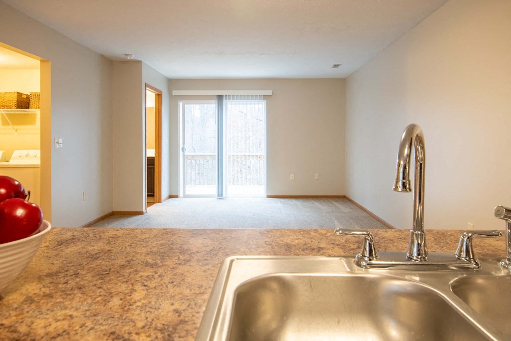 a kitchen with a sink and an empty living room