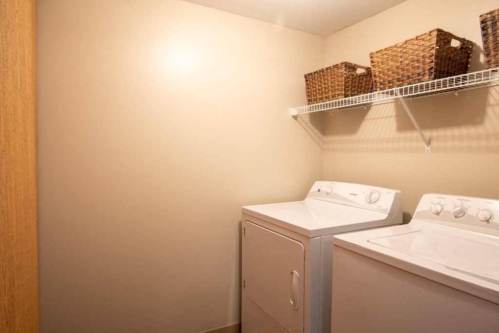 a white washer and dryer in a laundry room with a shelf above it