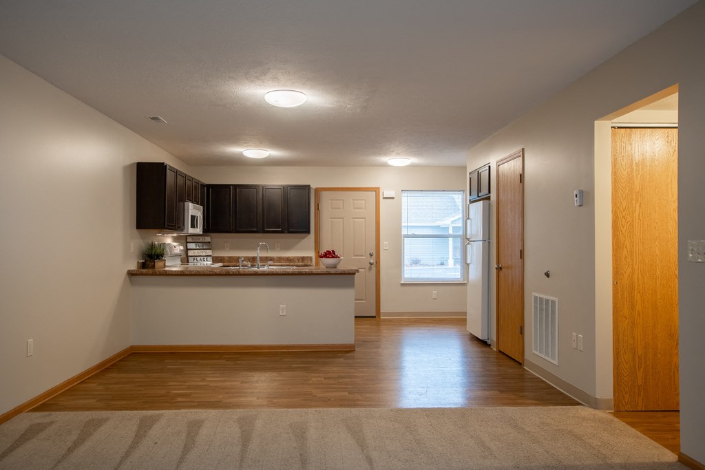 an empty living room and kitchen with a refrigerator and a sink