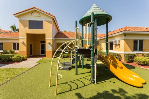 a playground in front of a house with a yellow slide