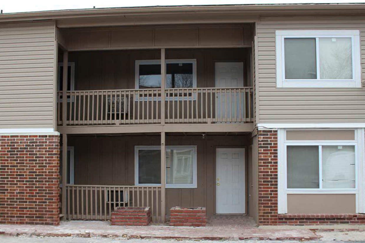 A two-story apartment building with a balcony on the second floor.