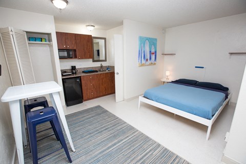 A small room with a bed, a table, and a refrigerator.
