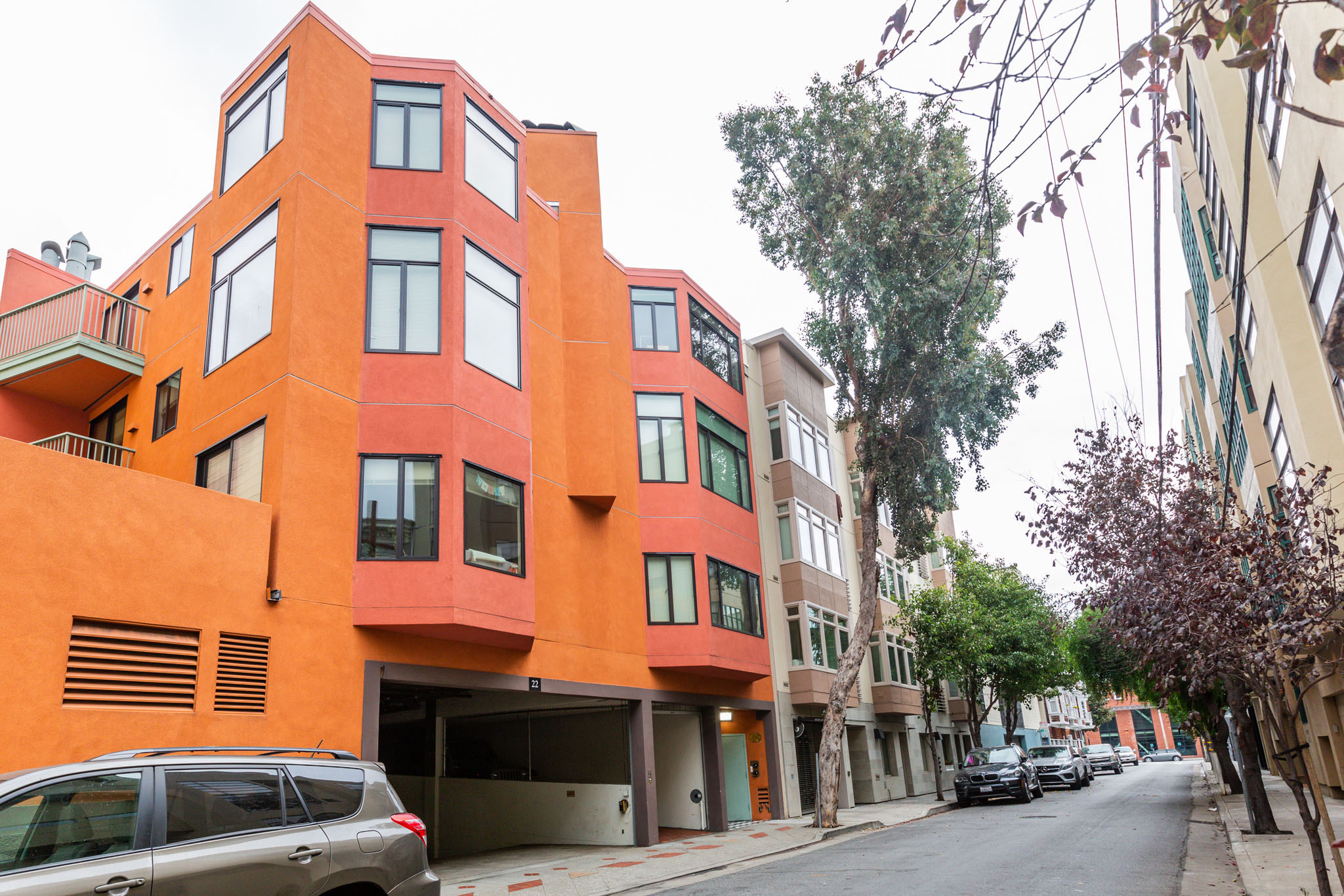 A street view of a red building with a car parked in front.