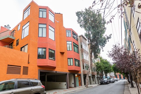 A street view of a red building with a car parked in front.