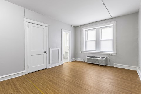 an empty room with white walls and wood floors and an air conditioner
