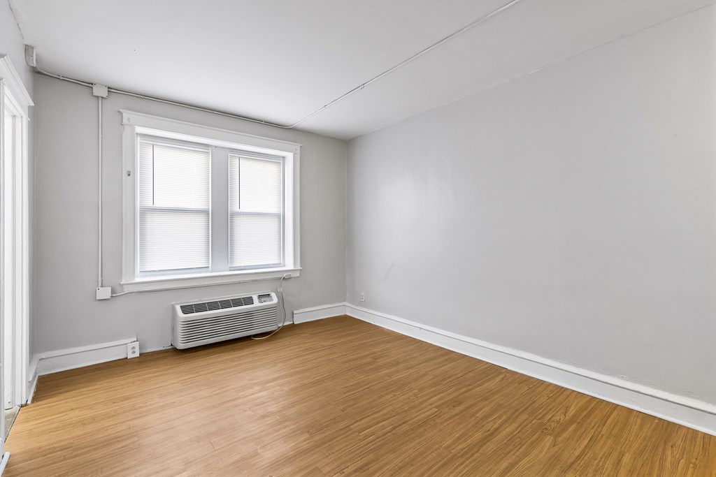 an empty room with wood floors and a window