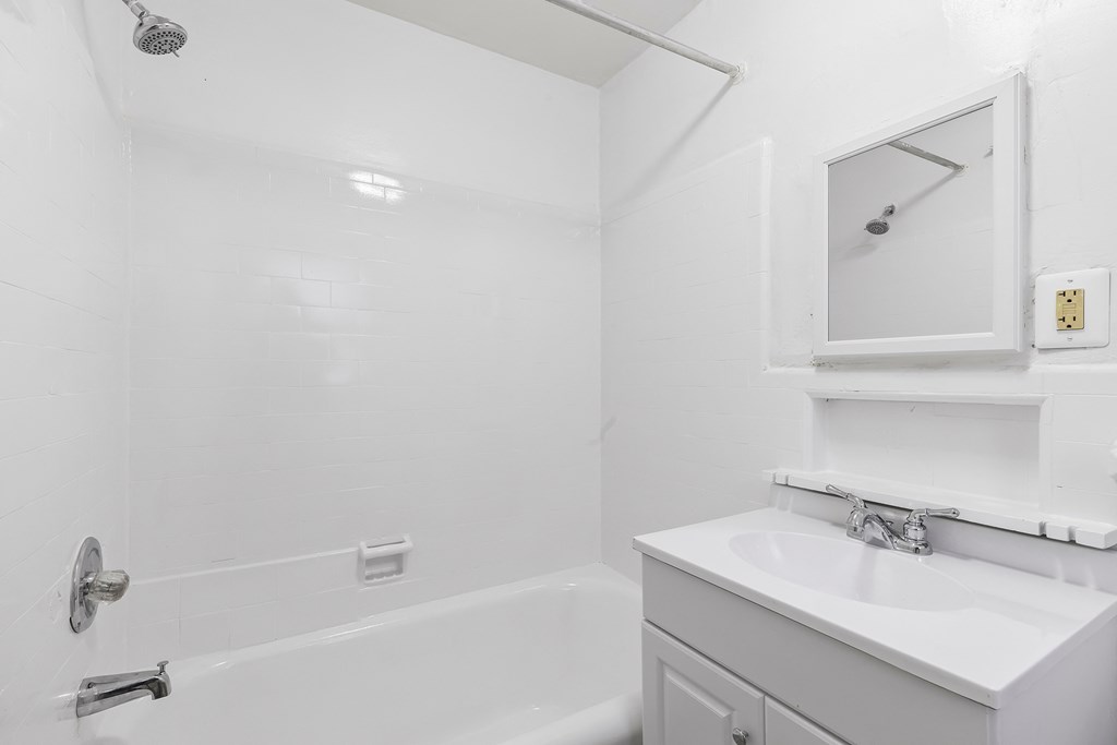 a white bathroom with a sink and a tub and a mirror
