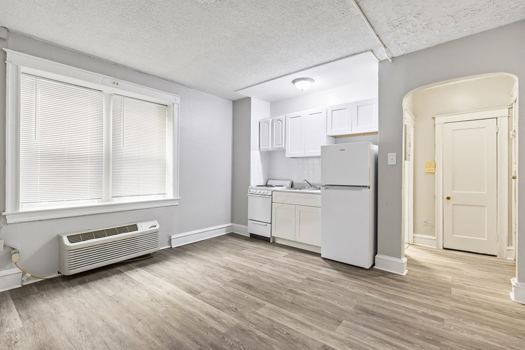 an empty kitchen with a refrigerator and a window