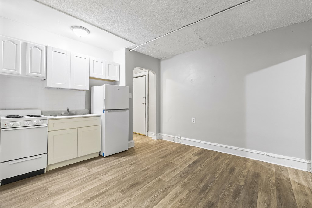 an empty kitchen with white cabinets and a refrigerator and a sink