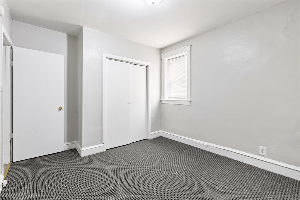 an empty room with white walls and a door to a closet