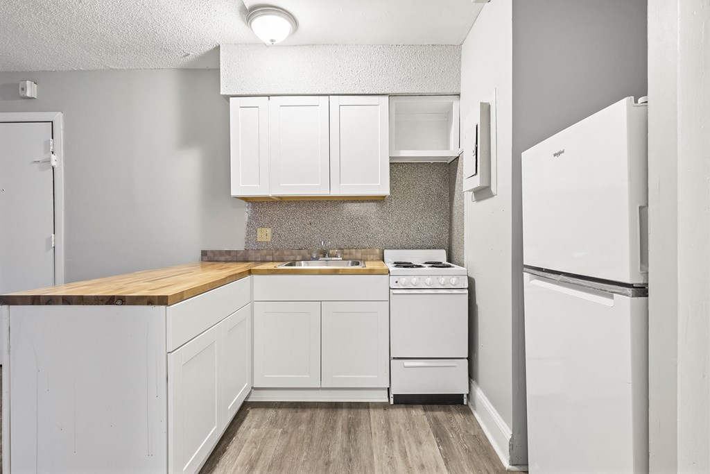 a white kitchen with white appliances and a wooden counter top
