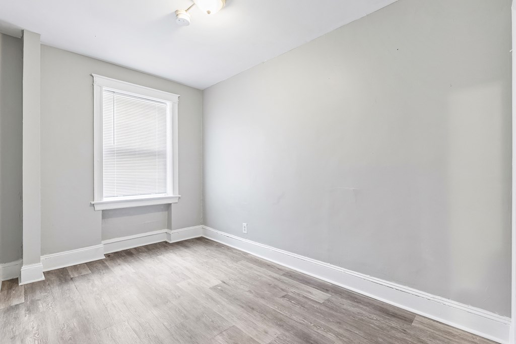 an empty room with white walls and wood floors and a window