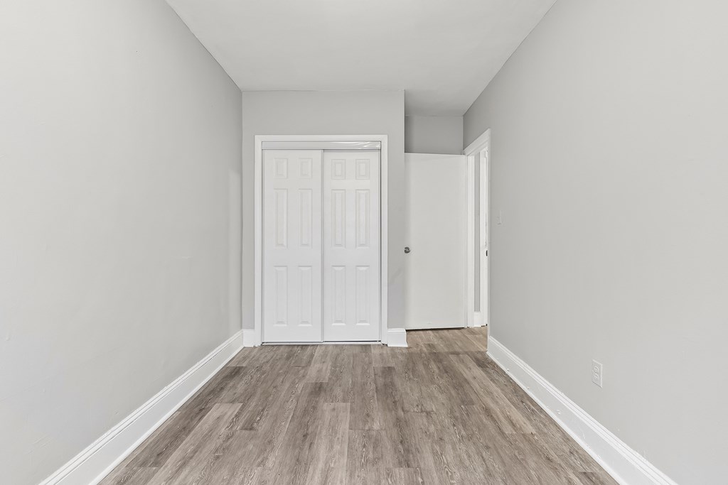 an empty room with white walls and wood floors and a white door