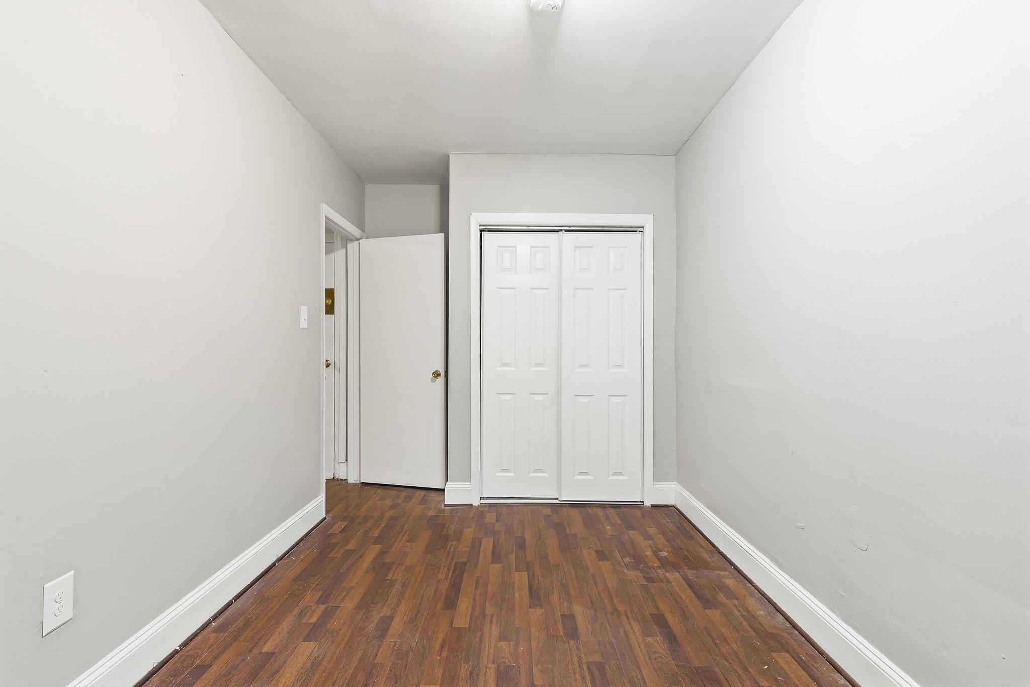 an empty room with wood flooring and white walls