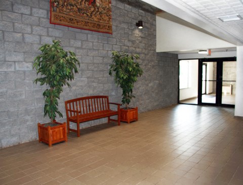 a large lobby with a bench and two potted plants