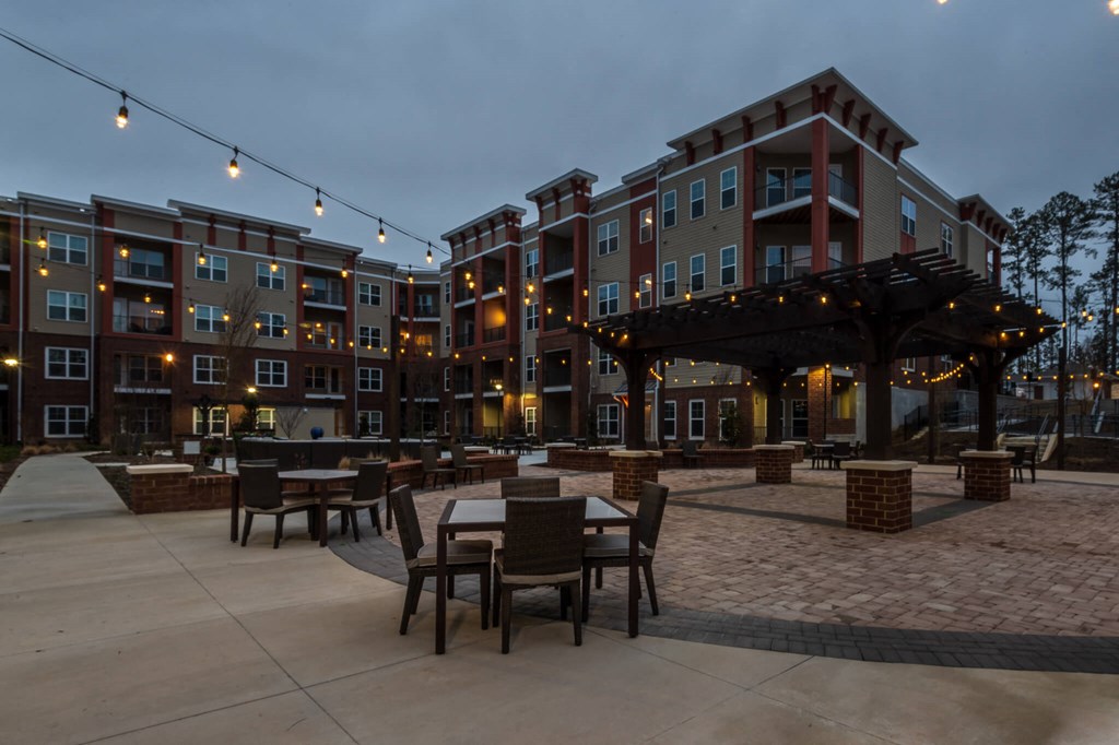 an outdoor patio with tables and chairs at dusk