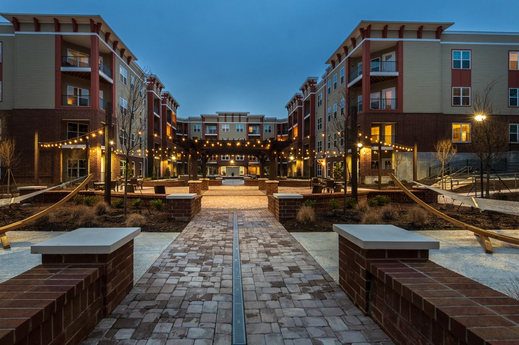 an open courtyard with benches and buildings at night