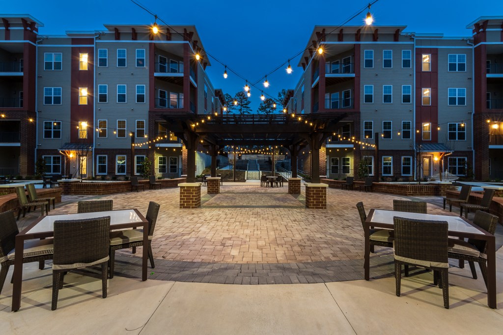a large courtyard with tables and chairs at night