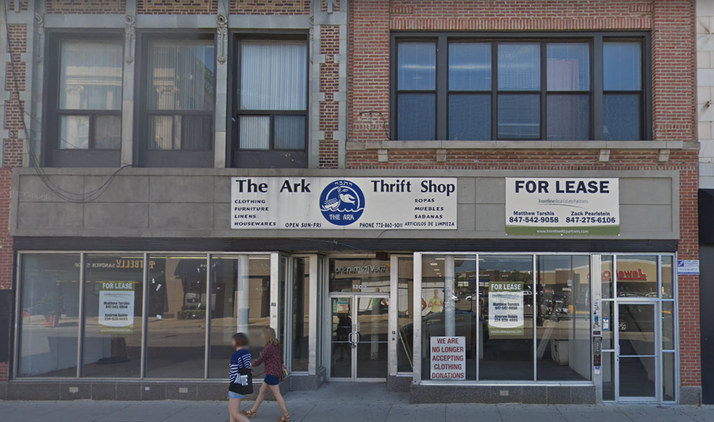 people walk past the front of the air thrift shop on a city street