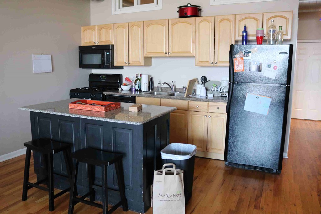 a kitchen with a refrigerator and a counter with three stools