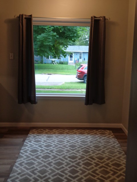 a living room with a window and a rug
