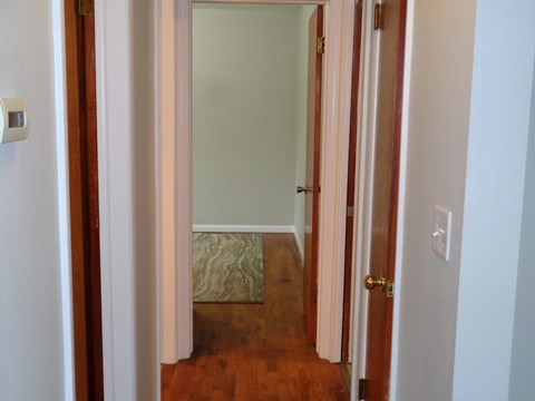 a small hallway with a door to a bedroom and a rug on the floor