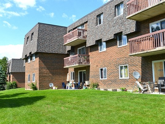 a large brick apartment building with balconies and a lawn