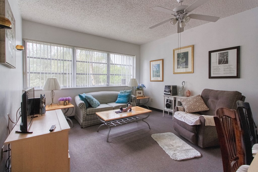 living room with ceiling fan and large window bank