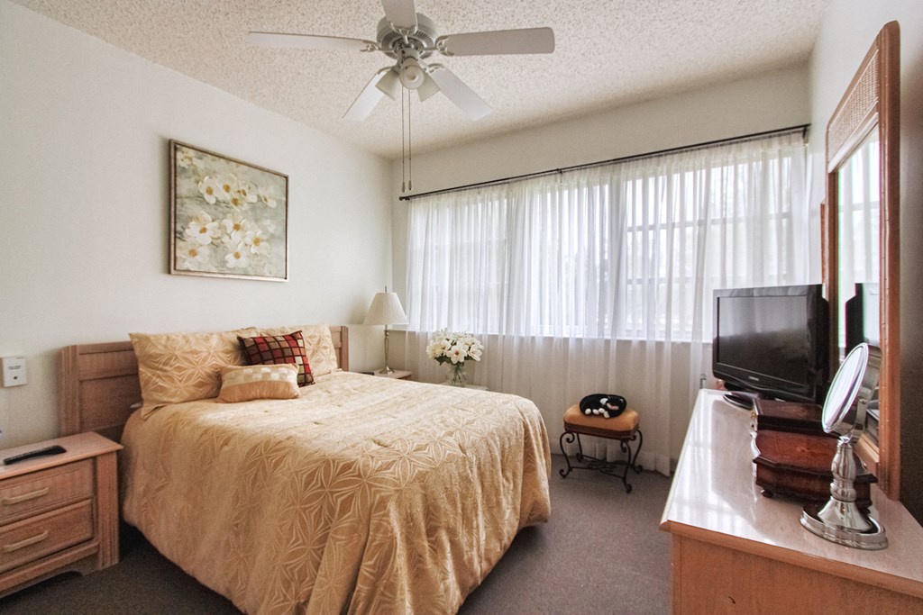 bedroom with large bank of windows and ceiling fan