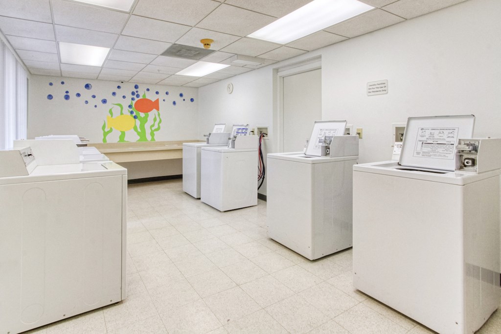 laundry center with washers, dryers, and folding tables