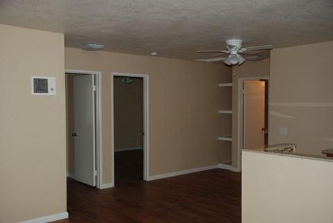 an empty living room with a ceiling fan and a closet