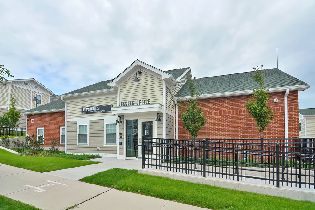 the exterior of a school building with a black fence and grass