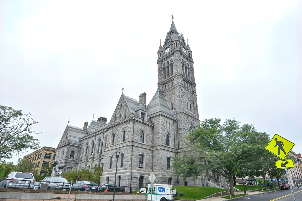 a large stone building with a tall tower and a street with cars