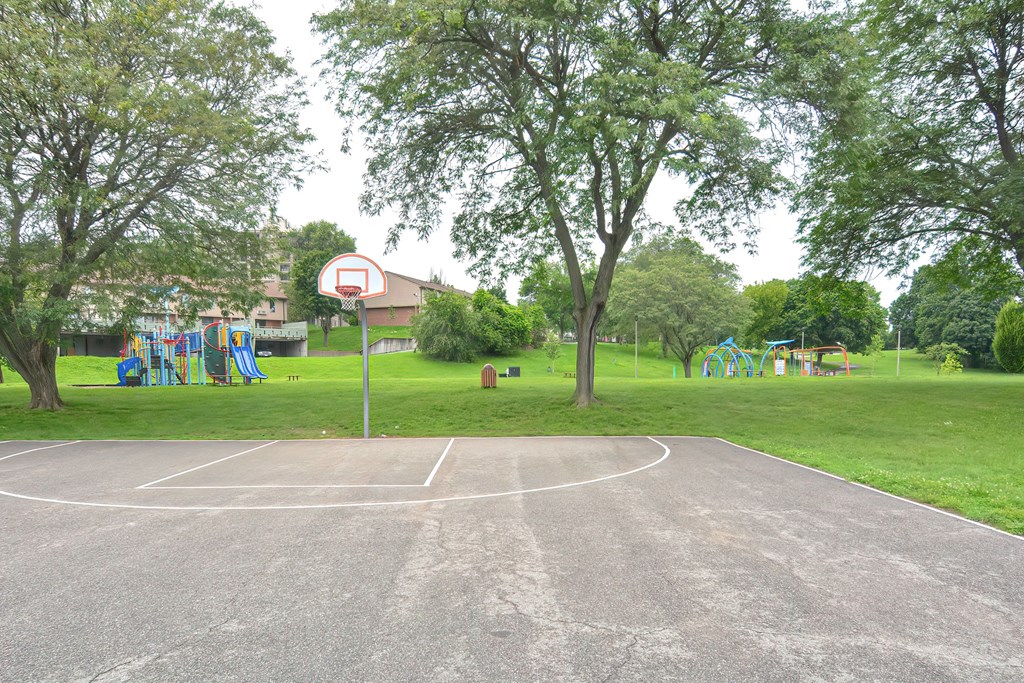 a basketball court with a playground in a park