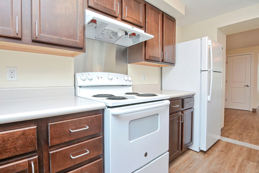 an empty kitchen with white appliances and wooden cabinets