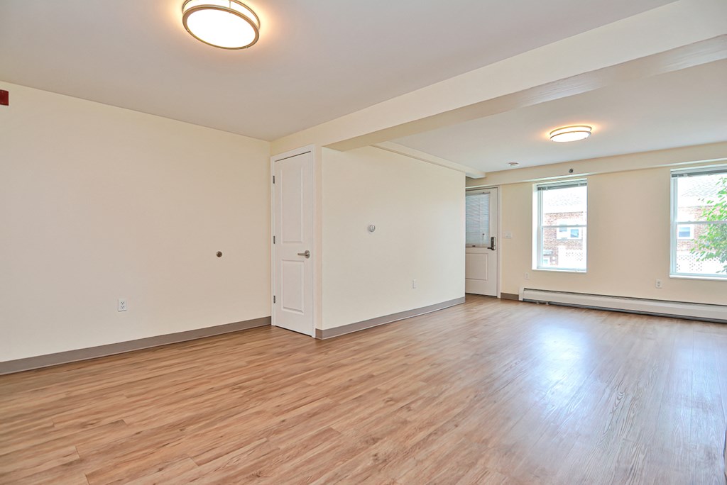 an empty living room with wood floors and white walls