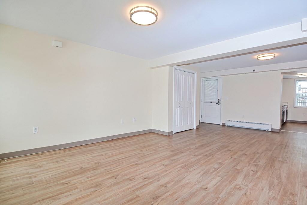 an empty living room with wood flooring and white walls