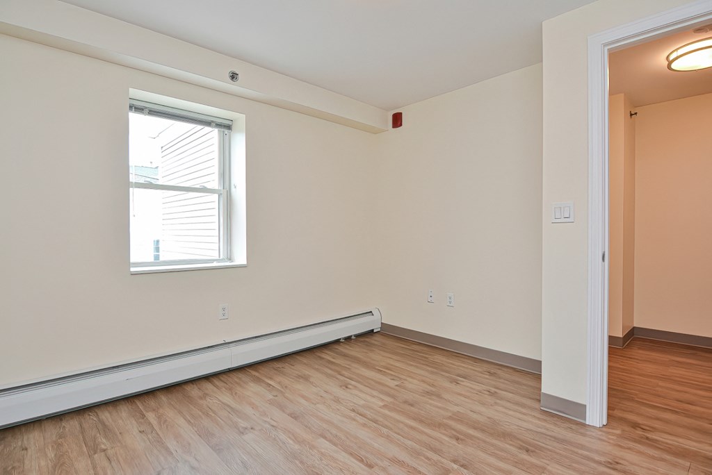 the living room of an empty apartment with wood flooring and a window