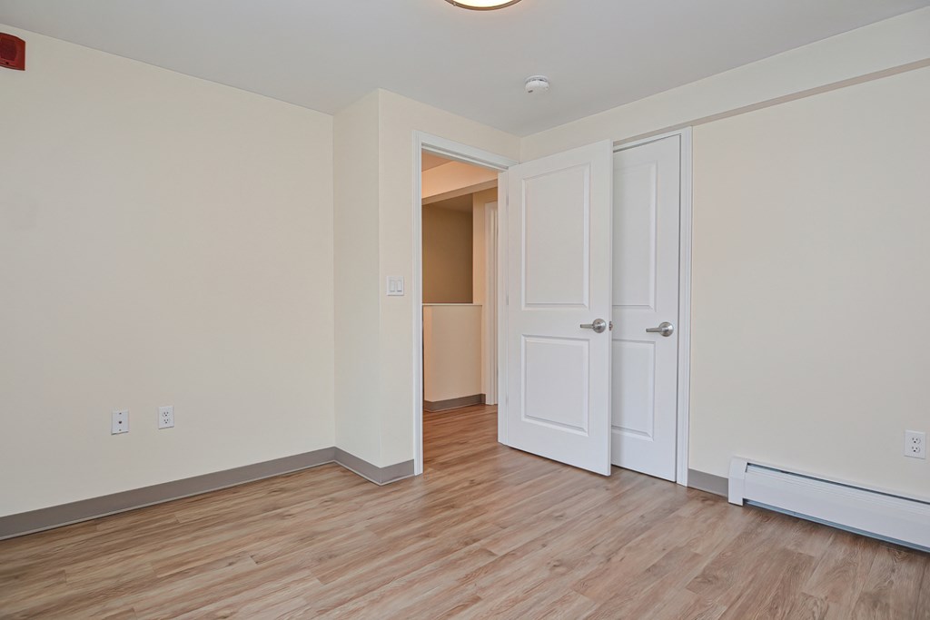 an empty living room with wood flooring and a door to a closet