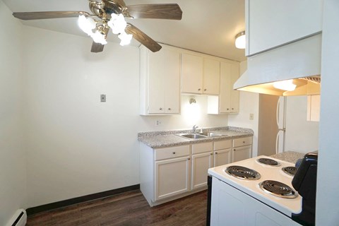 a kitchen with white cabinets and a stove and a ceiling fan