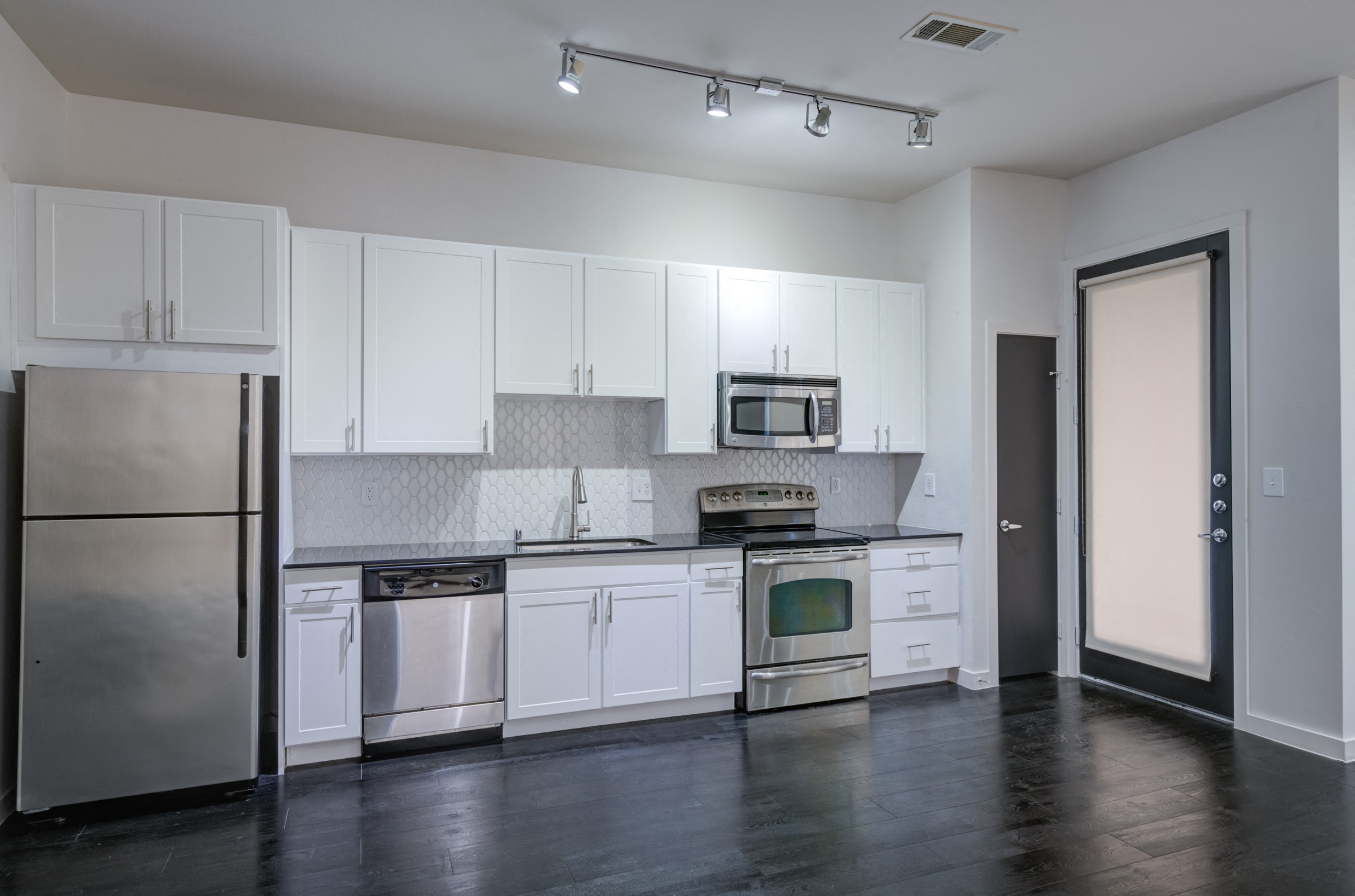 an empty kitchen with white cabinets and stainless steel appliances