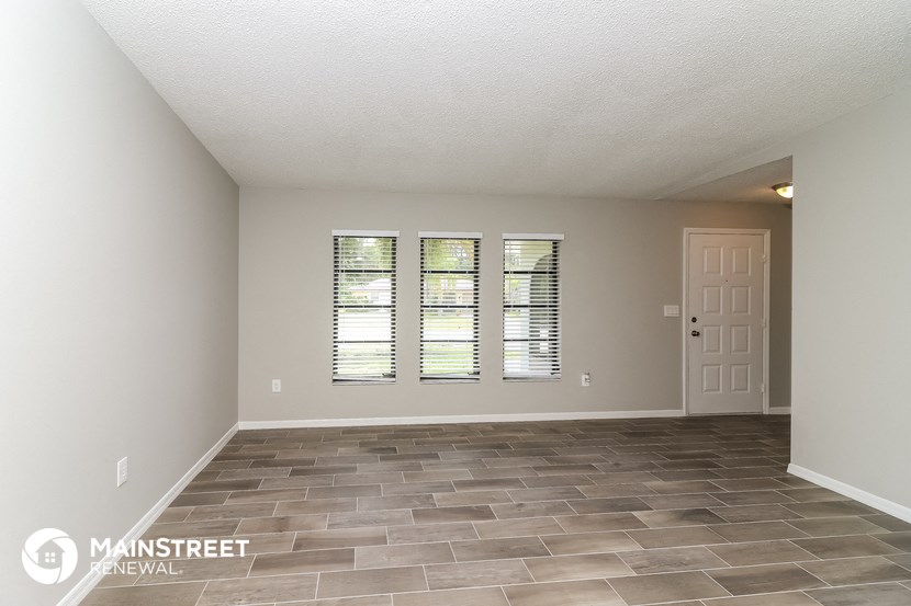 the spacious living room with tile flooring and a white door