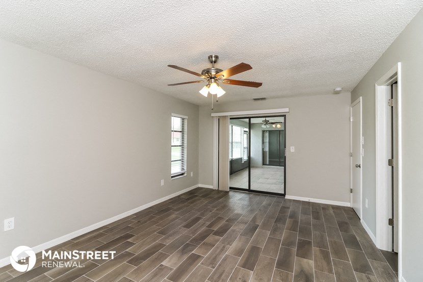 the living room is spacious and has a ceiling fan