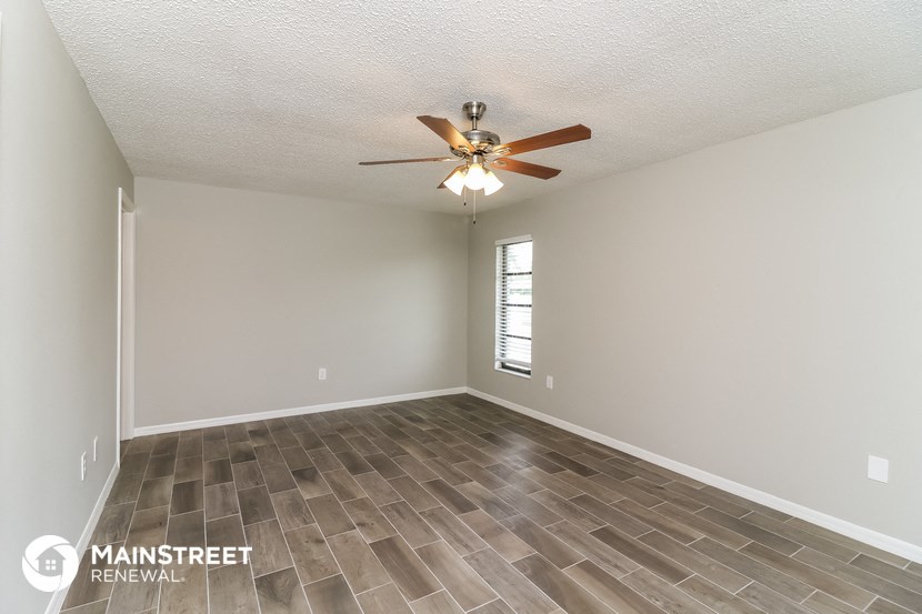 the spacious living room with vinyl flooring and a ceiling fan