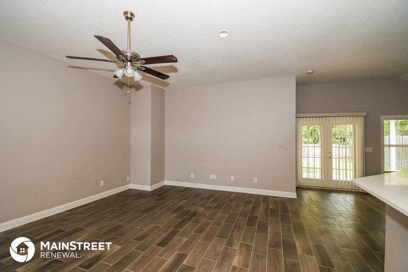 the spacious living room with wood flooring and a ceiling fan