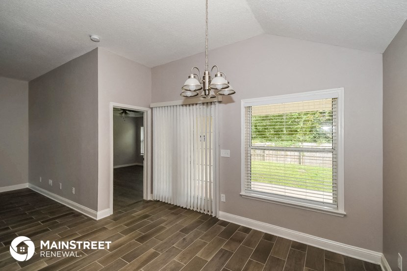 the living room of a home with a large window and wood flooring